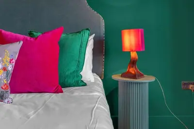 a bed with colorful pillows and a red lamp on a table at GuestReady - Unique hideaway in Edinburgh in Edinburgh