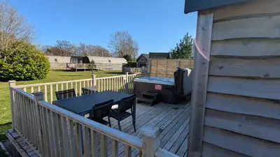 a wooden deck with a table and a grill at The Dochart Lodge with hot tub Braidhaugh Crieff in Crieff