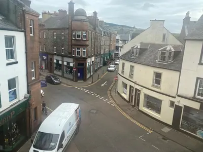 a white van driving down a city street with buildings at Spacious 3 bedroom apartment in Campbeltown centre in Campbeltown