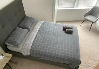 a bedroom with a bed with a pillow and a chair at Spacious 3 bedroom apartment in Campbeltown centre in Campbeltown