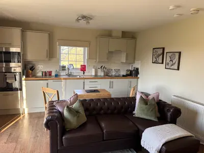 a living room with a couch and a kitchen at The Loch Lomond But n Ben in Gartocharn