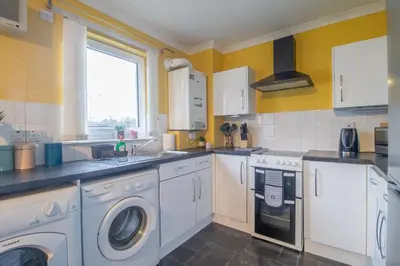 a kitchen with white appliances and yellow walls at Ideal Contractor Stay 2-Bed Near Glasgow Fort in Garthamlock