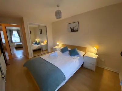 a bedroom with a large bed and a mirror at Apartment in Heart of West End- Parking Space- Spacious- Near Glasgow University and Kelvingrove Art Gallery in Glasgow