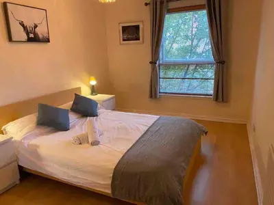 a bedroom with a bed with white sheets and a window at Apartment in Heart of West End- Parking Space- Spacious- Near Glasgow University and Kelvingrove Art Gallery in Glasgow