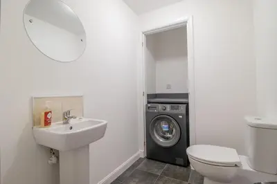 a bathroom with a sink and a washing machine at Lendrick House-Spacious 3 Bed House in Falkirk in Polmont