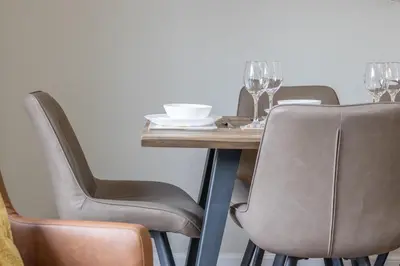 a wooden table with chairs and a table with wine glasses at Lendrick House-Spacious 3 Bed House in Falkirk in Polmont