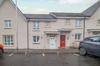 a house with a red door and a car parked in front at Lendrick House-Spacious 3 Bed House in Falkirk in Polmont