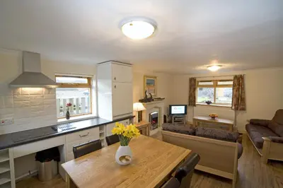 a kitchen and living room with a table with flowers on it at Clan Cottages Luxury Thatched Retreat near Oban in Oban