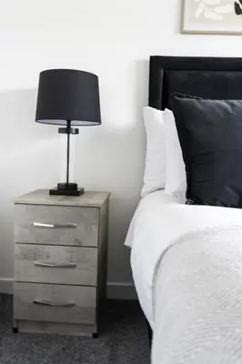 a bed with a night stand with a lamp on it at Charlotte Apartment in Glasgow