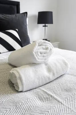 a pile of white towels sitting on a bed at Charlotte Apartment in Glasgow