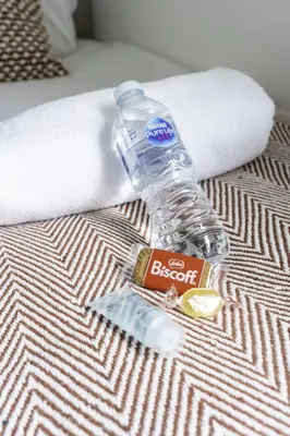a bottle of water sitting on top of a bed at Charlotte Apartment in Glasgow