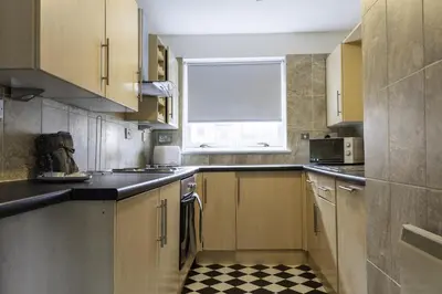 a kitchen with wooden cabinets and a checkered floor at Riverview House in Glasgow