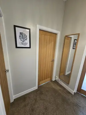 a hallway with a wooden door and a mirror at Ocean View 2 in Campbeltown