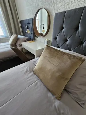 a bedroom with a bed with a chair and a mirror at Ocean View 2 in Campbeltown