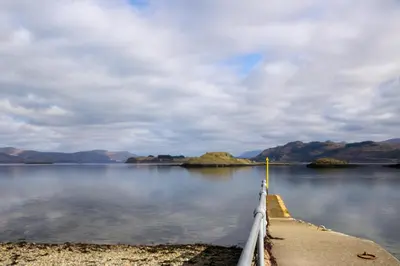 a dock on a lake with mountains in the background at The Old House, Balure in Oban