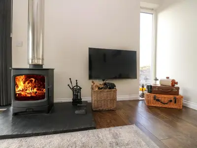 a living room with a fireplace and a flat screen tv at The Old House, Balure in Oban