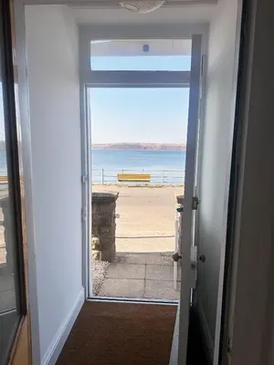 an open door with a view of the ocean at Bay View Cottage in Fairlie