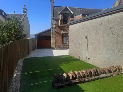 a yard with green grass next to a building at Bay View Cottage in Fairlie