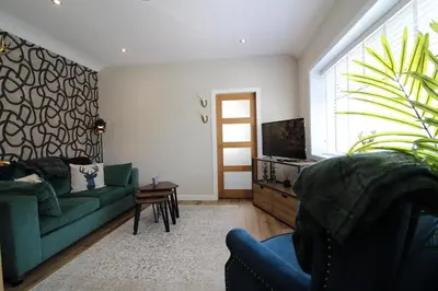 a living room with a green couch and a tv at Links Cottage, Prestwick in Prestwick