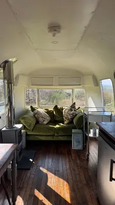 a couch in the middle of a van with pillows at Luxury Airstream Getaway with Sauna and Hot Tub in Gartness