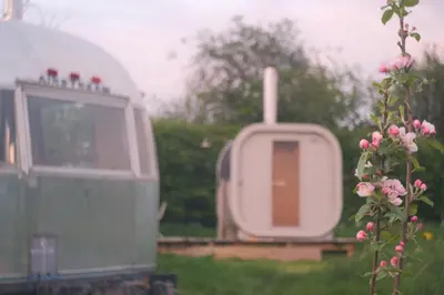 a truck parked in the grass next to a flower at Luxury Airstream Getaway with Sauna and Hot Tub in Gartness