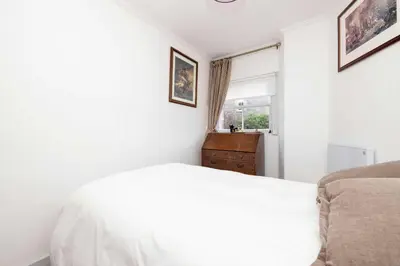 a white bedroom with a bed and a window at JOIVY Spacious 2-Bedroom Ground Floor Flat in Edinburgh