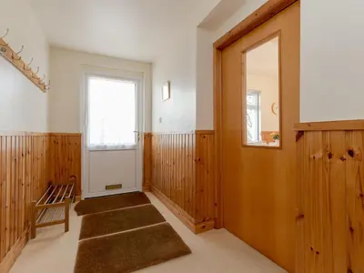 a hallway with a door and a chair and a window at Holiday Home Doonans Cottage by Interhome in Straiton