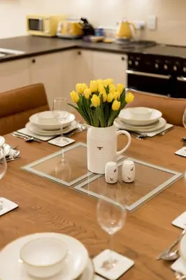 a table with a vase of yellow flowers on it at Holiday Home Balbeg Cottage by Interhome in Straiton