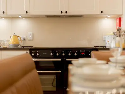 a kitchen with an oven and a table with dishes at Holiday Home Balbeg Cottage by Interhome in Straiton
