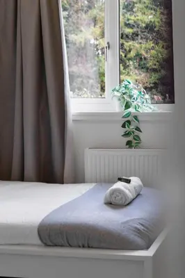 a bed with a towel on it in front of a window at Vacant Nests The Livingston Retreat Wi-Fi in Uphall