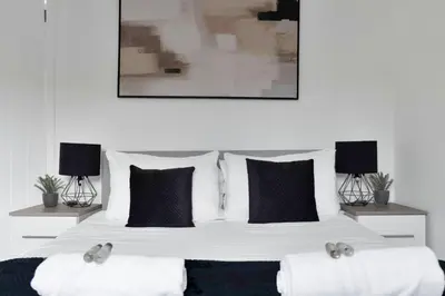 a bedroom with a large bed with black and white pillows at Vacant Nests The Livingston Retreat Wi-Fi in Uphall