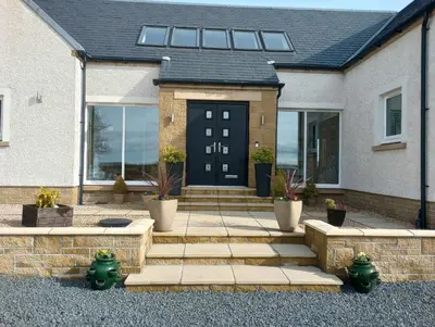 a house with a black door and a patio at East Laigh Gree Bed and Breakfast in Burnhouse