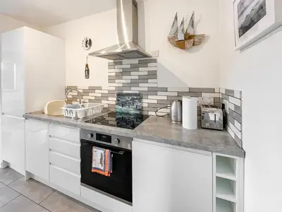 a kitchen with white cabinets and a stove top oven at Ardtornish Apartment in Tayvallich