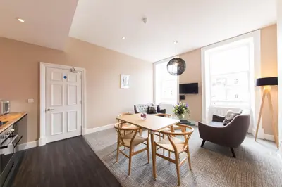 a kitchen and living room with a table and chairs at The Spires Serviced Apartments Edinburgh in Edinburgh