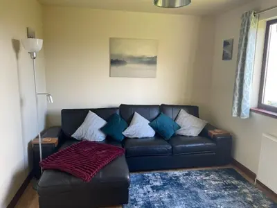 a living room with a black leather couch with pillows at The Roost in Appin