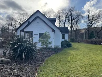 a small white house with a grass yard at The Roost in Appin