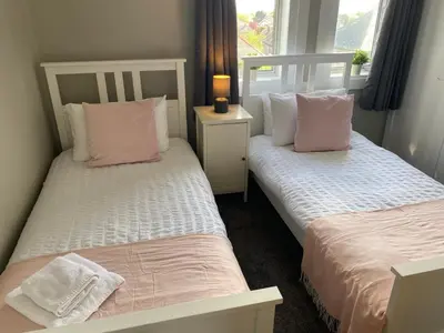 two beds with pink and white pillows in a room at Glen Mhor - Beautiful two bedroom apartment Dunfermline in Townhill