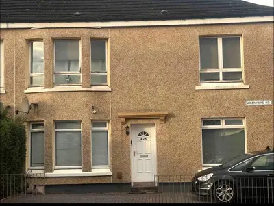 a brick house with a white door and a car at Home to Home in Glasgow