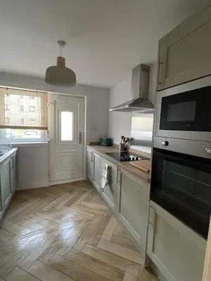 a kitchen with white cabinets and wooden floors at 2 Bed on the Glasgow Green in Glasgow