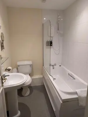 a bathroom with a toilet and a tub and a sink at Gordon Arms Hotel in West Linton