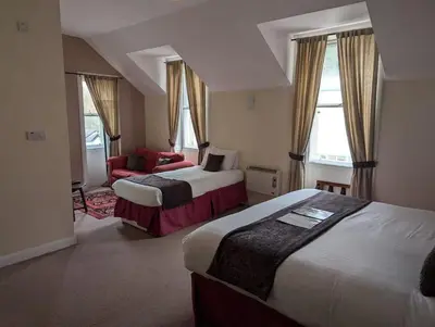 a hotel room with two beds and a red chair at Gordon Arms Hotel in West Linton