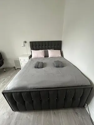 a large bed in a white room with a bed frame at Bright bedroom with king side bed and share bathroom in Edinburgh