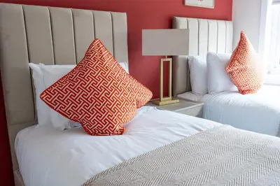 a bedroom with two beds with pillows on them at Beauly Court Suites in Grangemouth