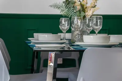 a table with plates and glasses on a green wall at Arran Cottage - 4 Bed Home on M8 in Coatbridge
