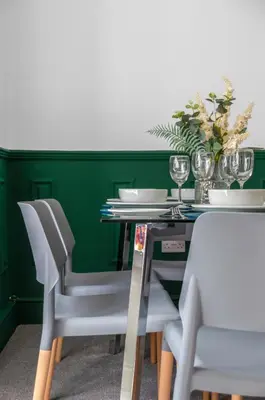 a dining table with white chairs and a green wall at Arran Cottage - 4 Bed Home on M8 in Coatbridge