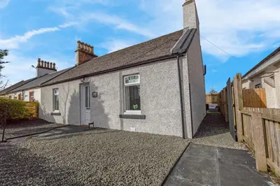a brick house with a window and a fence at Arran Cottage - 4 Bed Home on M8 in Coatbridge