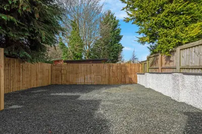 a backyard with a wooden fence and a driveway at Arran Cottage - 4 Bed Home on M8 in Coatbridge