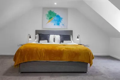 a bedroom with a large bed with a yellow blanket at Arran Cottage - 4 Bed Home on M8 in Coatbridge