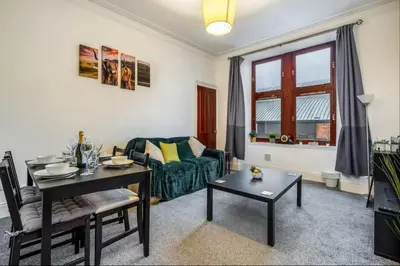 a living room with a couch and a table at Cheerful 1 Bedroom Homely Apartment, Sleeps 4 Guest Comfy, 1 x Double Bed, 1 x Sofa Bed, Parking, Free WiFi, Suitable For Business, Leisure Guest,Glasgow, Glasgow West End, Near City Centre, Perfect for Common Wealth Games 2026 in Glasgow