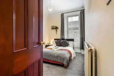 a bedroom with a bed and a window at Cheerful 1 Bedroom Homely Apartment, Sleeps 4 Guest Comfy, 1 x Double Bed, 1 x Sofa Bed, Parking, Free WiFi, Suitable For Business, Leisure Guest,Glasgow, Glasgow West End, Near City Centre, Perfect for Common Wealth Games 2026 in Glasgow